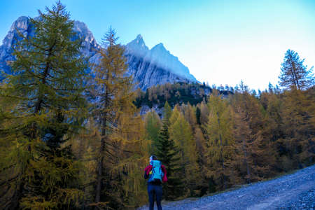 A woman with big hiking backpack walking through a stony pathway to reach the Grosse Gamswiesenspitze in Lienz Dolomites, Austria. Sharp and barren slopes. Massive Alpine mountains. Solo wandererの写真素材