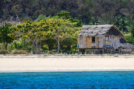 A distant view on a fishing cottage, located on a seashore of a small island next Flores, Indonesia. Clear, turquoise coloured water displaying coral reef. Solitude and calmness. Simple constructionの写真素材