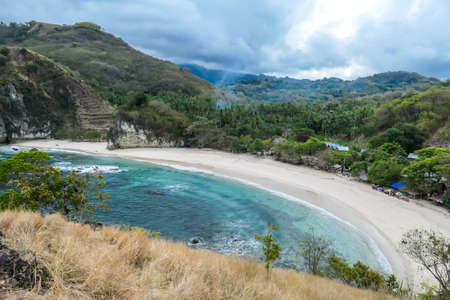 A view on idyllic Koka Beach from a nearby headland. Hidden gem of Flores, Indonesia. Beach is gently washed by waves. Serenity and calmness. Island life. Beach surrounded by mountains.の写真素材