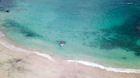 Top-down drone shot of an idyllic Koka Beach. Hidden gem of Flores Indonesia. Beauty in the nature. Calm waves washing the sandy shore gently. Serenity and calmness. There are some boulders in the seaの写真素材