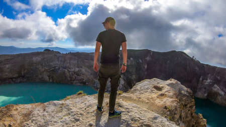 Man standing at the volcano rim and watching the Kelimutu volcanic crater lakes in Moni, Flores,...