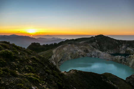 Sunrise over the Kelimutu volcanic crater lakes in Moni, Flores, Indonesia. Skyline is bursting with orange. Turquoise color of the lake. Golden hour colours the surroundings. Beauty of the natureの写真素材
