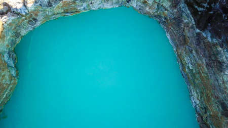 A drone top-down shot of volcano Kelimutu's crater lake in Flores, Indonesia. The lake has a very strong turquoise colour thanks to the minerals in the water. Natural phenomenonの写真素材