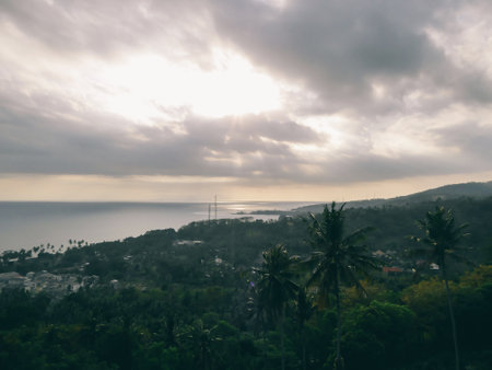 Sunset on Lombok in Indonesia, seen from a high hill. Beautiful warm colored sunlight reflections on the water surface. In the distance Mount Agung can be seen,  an active volcano on Bali.の写真素材