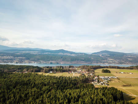 Areal, drone view on Schiefling am See, Austria. The village is located between Alps chains. There is a thick and dense forest all around. harmonious living with nature.の写真素材