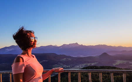 Sunset in the sunglasses of a girl, Pyramidenkogel, Woerthersee. Girl is holding a barrier, the wind...