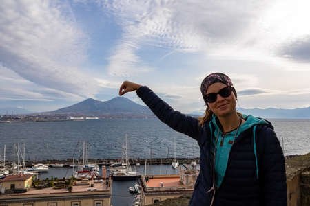 A tourist woman pointing the finger on the peak of volcano mount Vesuvius. Scenic view from Castel...