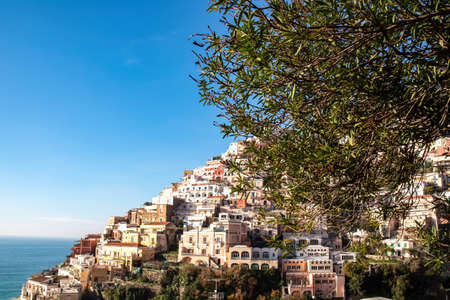 Panoramic view on colorful houses of coastal town Positano, Amalfi Coast, Italy, Campania, Europe. Branch of tree in foreground. Vacation at coastline at Tyrrhenian, Mediterranean Sea. Path of Godsの写真素材