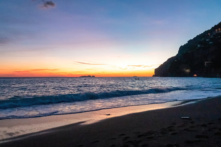 Panoramic sunset view from Marina Grande beach in Positano at Amalfi Coast, Italy, Campania, Europe. Silhouette of coastline. Orange twilight over Li Galli islands in Mediterranean Sea. Reflectionの写真素材