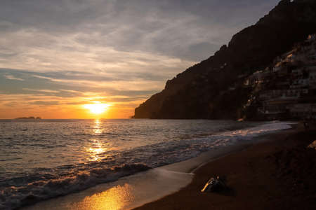 Panoramic sunset view from Marina Grande beach in Positano at Amalfi Coast, Italy, Campania, Europe. Silhouette of coastline. Orange twilight over Li Galli islands in Mediterranean Sea. Reflectionの写真素材