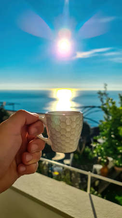 A person enjoying a cup of coffee with scenic view on the Mediterranean Sea near Amalfi Coast,...