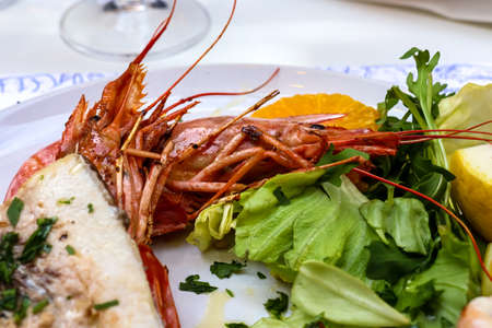 Close up view on a traditional Italian meal with grilled octopus, shrimp, scampi. Delicious fish plate in a testaurant in Syracuse, Sicily, Italy, Europe EU. Mediterranean cuisine. Seafoodの写真素材