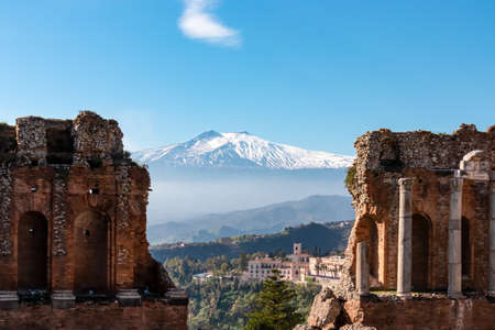 Panoramic view of snow capped Mount Etna volcano on a sunny day seen from the ancient Greek theater of Taormina, island Sicily, Italy, Europe, EU. Travel destination at the Mediterranean sea. Tourismの写真素材