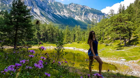 A woman standing on a blossoming meadow in an Alpine valley in Austria. The spring in the valley....