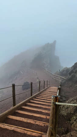 Wooden hiking trail along foggy edge of active volcano crater of Mount Vesuvius, Province of Naples,...