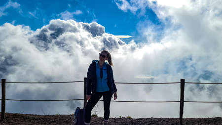 Happy woman with panoramic view from the summit of volcano Mount Vesuvius on thick white clouds over the bay of Naples, Campania region, Southern Italy, Europe, EU. Dreamy and magical hike. Aweの写真素材