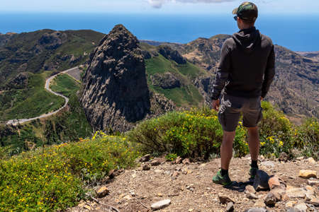 Man with scenic view on mountain road next to volcanic rock formation Roque de Agando in Garajonay National Park on La Gomera, Canary Islands, Spain, Europe. Seen from lookout Mirador Morro de Agandoの写真素材