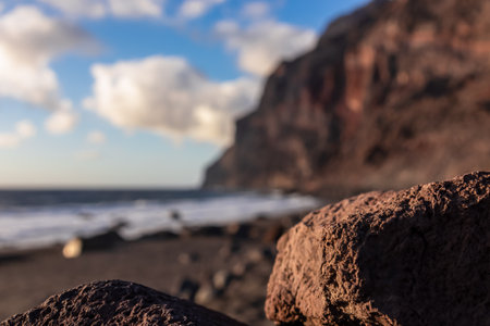 Scenic view during sunset on the volcanic sand beach Playa del Ingles in Valle Gran Rey, La Gomera, Canary Islands, Spain, Europe. Massive cliffs of the La Mercia range. Close up on Rock formationの写真素材