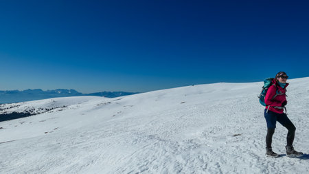 Woman hiking in snow covered landscape near Ladinger Spitz, Saualpe, Lavanttal Alps, Carinthia,...