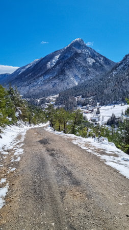 Winter wonderland landscape in Bleiberger Erzberg mountains in Bad Bleiberg, Carinthia, Austria, Europe. Road to remote village with scenic view on snow capped Dobratsch summit, Austrian Alpsの写真素材