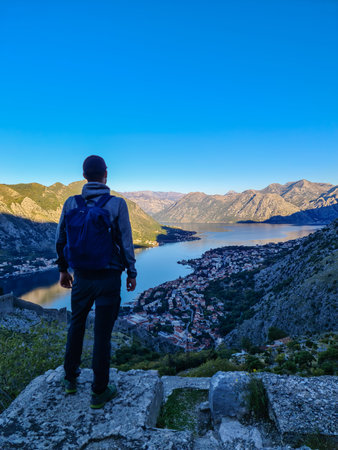 Man with panoramic view from the Ladder of Kotor on the Kotor bay during sunrise, Adriatic...