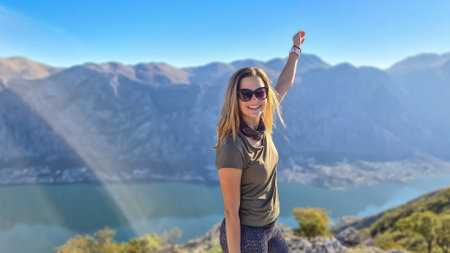 Woman with scenic view from mountain summit of Vrmac Sveti Ilija on Kotor bay in summer, Adriatic Mediterranean Sea, Montenegro, Balkans, Europe. Fjord winding along coastal towns. Hiking Dinaric Alpsの写真素材