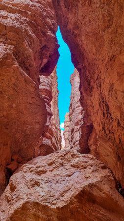 Narrow Navajo hiking trail through massive cliffs of hoodoo sandstone rock formation in Bryce Canyon National Park, Utah, USA. Barren desert landscape with view of natural amphitheatre in summerの写真素材
