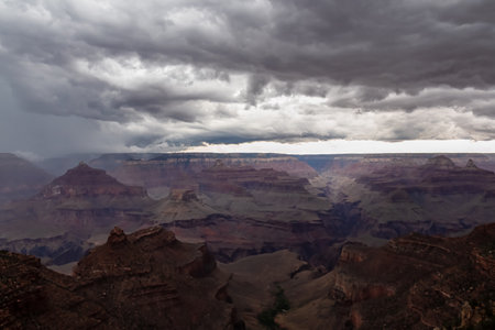 Dark clouds emerging to rain storm seen from the Bright Angel Point at South Rim of Grand Canyon National Park, Arizona, USA. Isolated summer cloudburst. Colorado River weaving through rugged terrainの写真素材