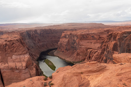 Tourist man at the cliff edge with panoramic aerial view of Horseshoe bend on the Colorado river near Page in summer, Arizona, USA. Incised meanders in Glen Canyon National Recreation Areaの写真素材