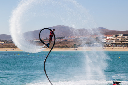 Fuerteventura, Spain - January 12, 2019: A man is doing acrobatics with flyboard attached to jet ski close to the harbor in caleta de fuste, Fuerteventura, Spainのeditorial素材