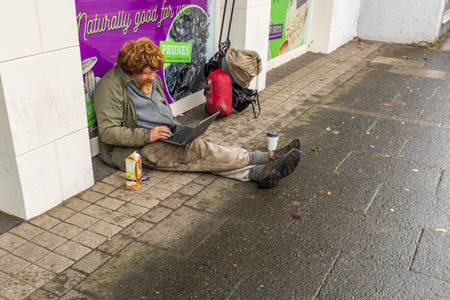 Homeless person sat on the floor with a laptopの写真素材