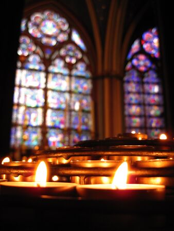 Prayer candles in Notre Dame Cathedral, Paris with out-of-focus stained glass in the background の写真素材