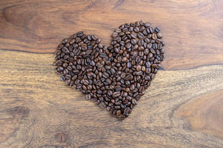 heart made of coffee beans on wooden tableの写真素材