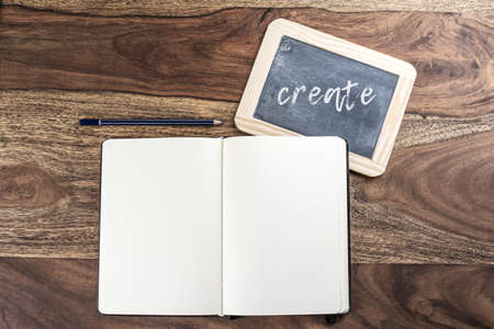 open plain empty page notebook with pencil and blackboard on rustic wood tableの写真素材