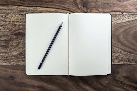 open plain notebook diary on dark wood desk with pencil の写真素材