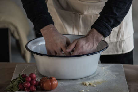 hands of a person kneading dough in a bowl on marble carving board on tableの写真素材