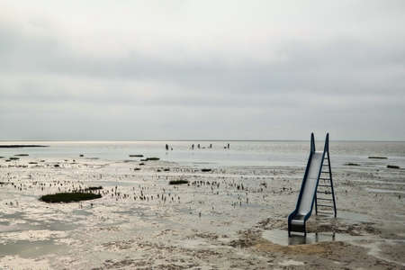 slide standing in mud at low tide at notrh sea coast in Germanyの写真素材