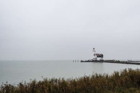coastline with old lighthouse on a grey and bleak dayの写真素材