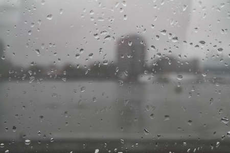 blurred cityscape seen through rain drops on wet window pane