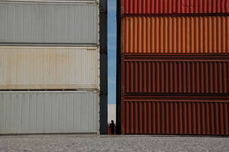 silhouette of person standing between stacks of cargo containersの写真素材