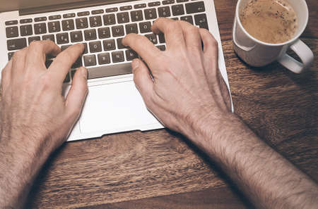 top view of the hands of a male person typing on a modern notebook keyboardの写真素材