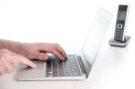hands of a male person working on a notebook laptop computer on white desk surface