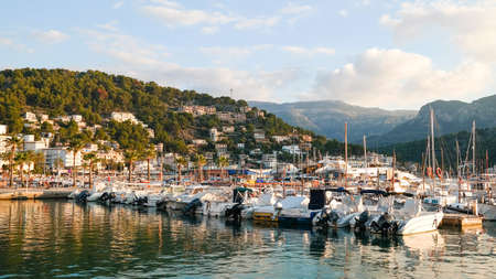 view of Port de Soller marina with Serra de Tramuntana mountains in background in beautiful evening sunlightの写真素材