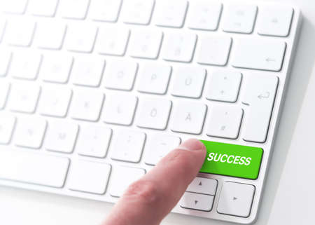 finger pressing a green key labeled SUCCESS on a computer keyboard, key to successの写真素材