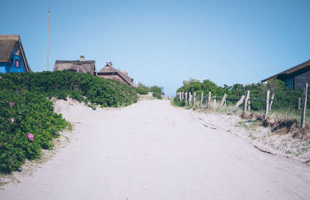 sand road on the Graswarder peninsula in Heiligenhafen, Germany lined with typical thatch-roofed housesの写真素材