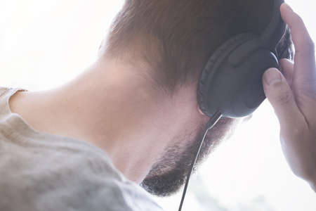 back view of the head of a young male person listening to music on headphonesの写真素材