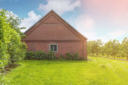 old brick stable shed on lush green meadow under blue sky