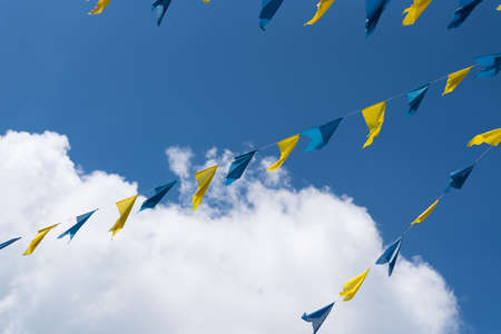 blue and yellow bunting flags against blue summer skyの写真素材