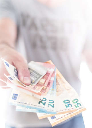 hand of male person handing over a couple of different euro billsの写真素材