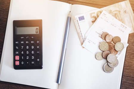 account book concept with cash bills and coins, notebook and calculator on rusitc wooden tableの写真素材